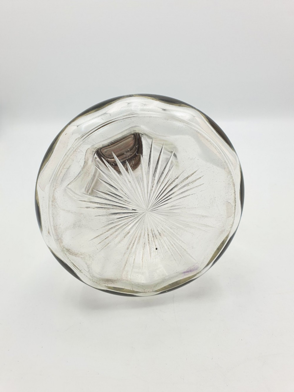 An Edwardian clear glass claret jug featuring a star-cut base, fluted body, angular silver handle, and sterling silver mounted spout with a domed lid. View VII