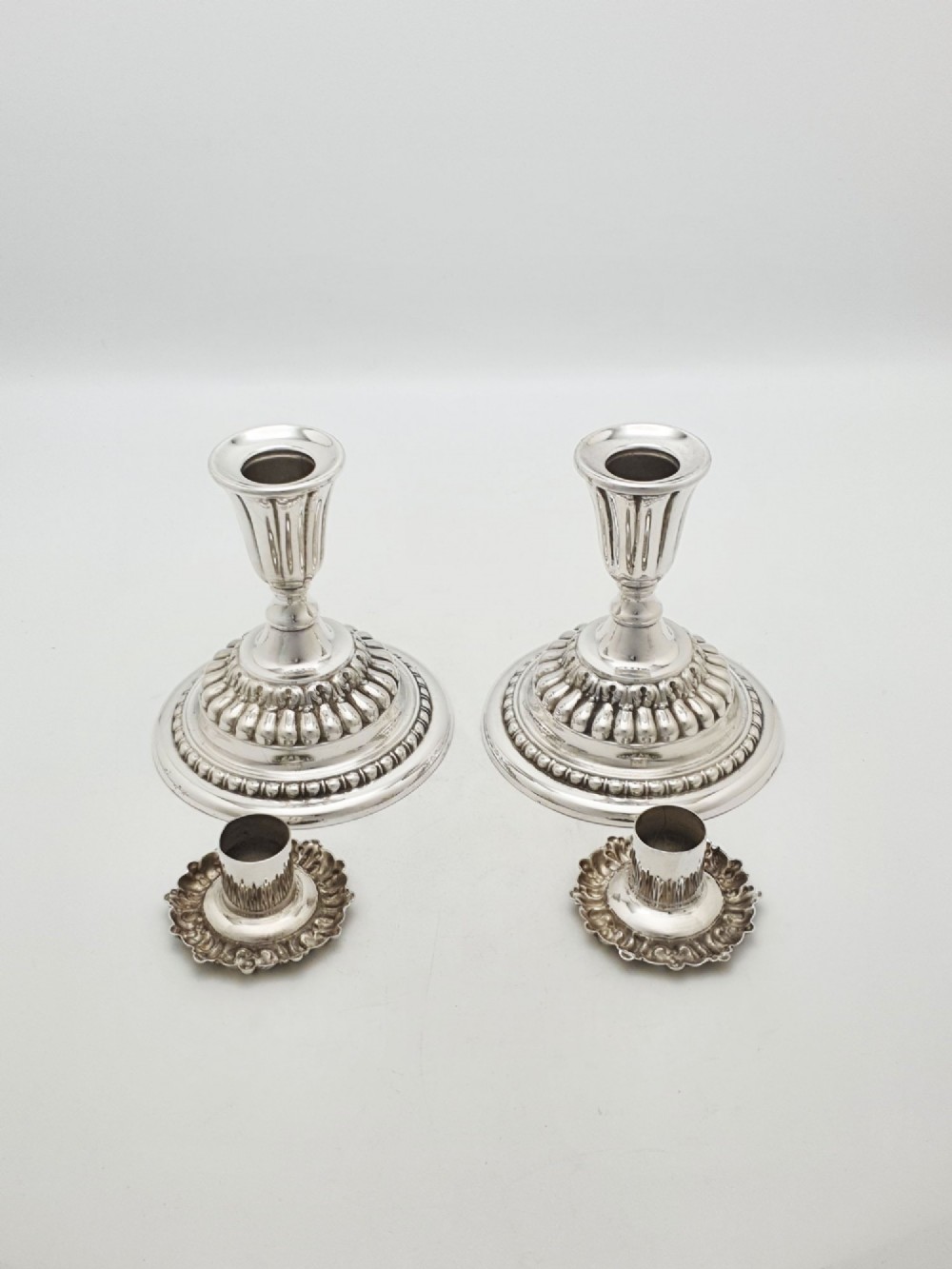 A pair of antique Edwardian low silver-plated candlesticks featuring fluted sockets and gadrooned circular bases. View III