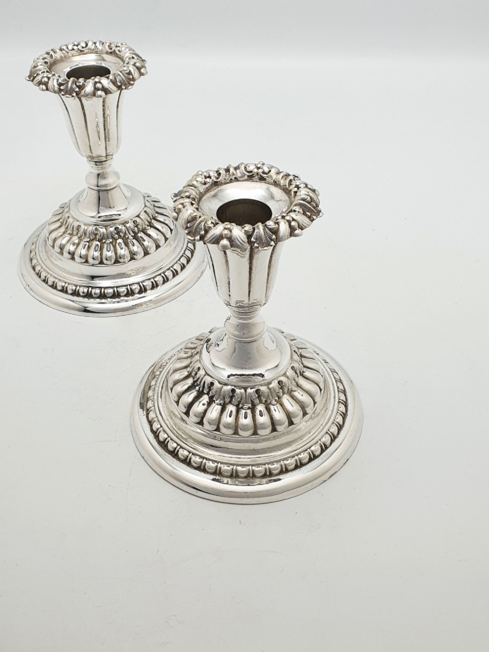 A pair of antique Edwardian low silver-plated candlesticks featuring fluted sockets and gadrooned circular bases. View IV