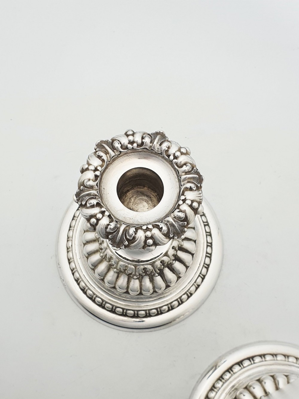 A pair of antique Edwardian low silver-plated candlesticks featuring fluted sockets and gadrooned circular bases. View VI