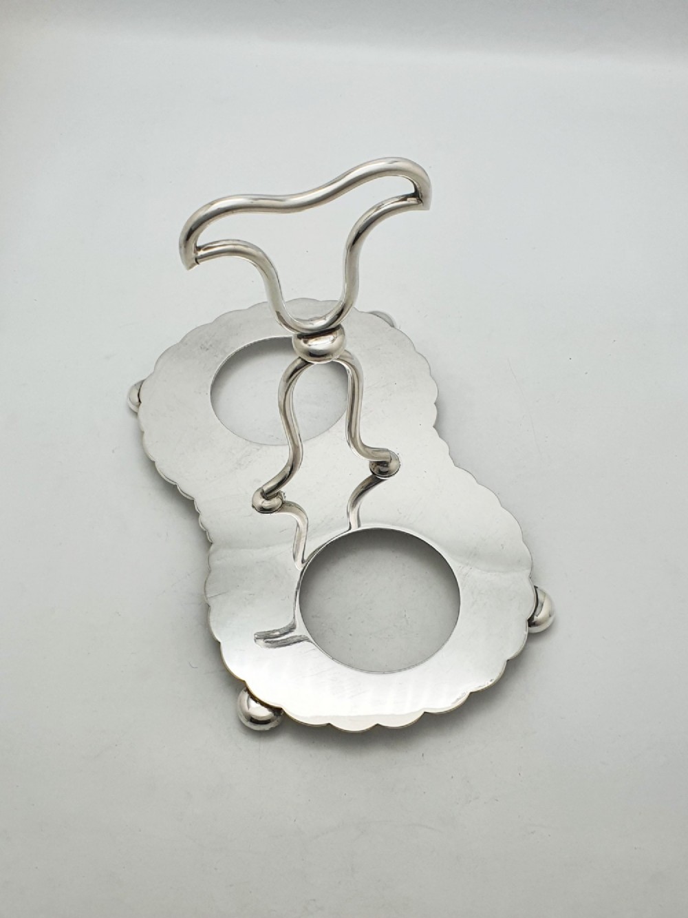 A silver-plated condiment stand featuring a central looped handle, ball feet, and two clear diamond-patterned glass bowls. View VI