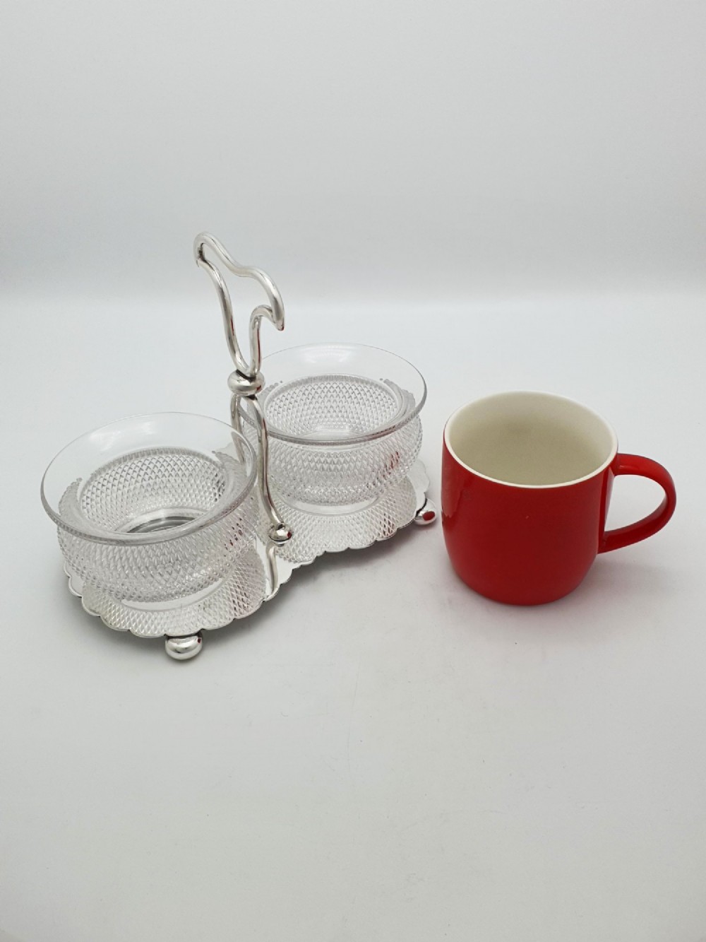 A silver-plated condiment stand featuring a central looped handle, ball feet, and two clear diamond-patterned glass bowls. View VIII