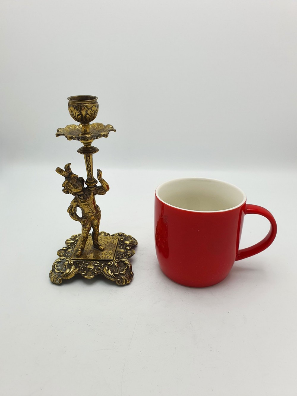 A pair of Victorian gilt brass candlesticks featuring sculpted figural stems raised on square ornamented bases with acanthus detail. View VIII