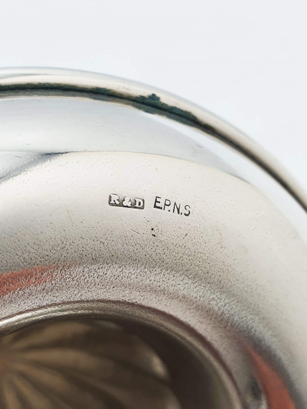 A silver-plated manual citrus squeezer featuring a central fluted reamer cone, a circular perforated strainer ring, and a shallow catch tray. View IV