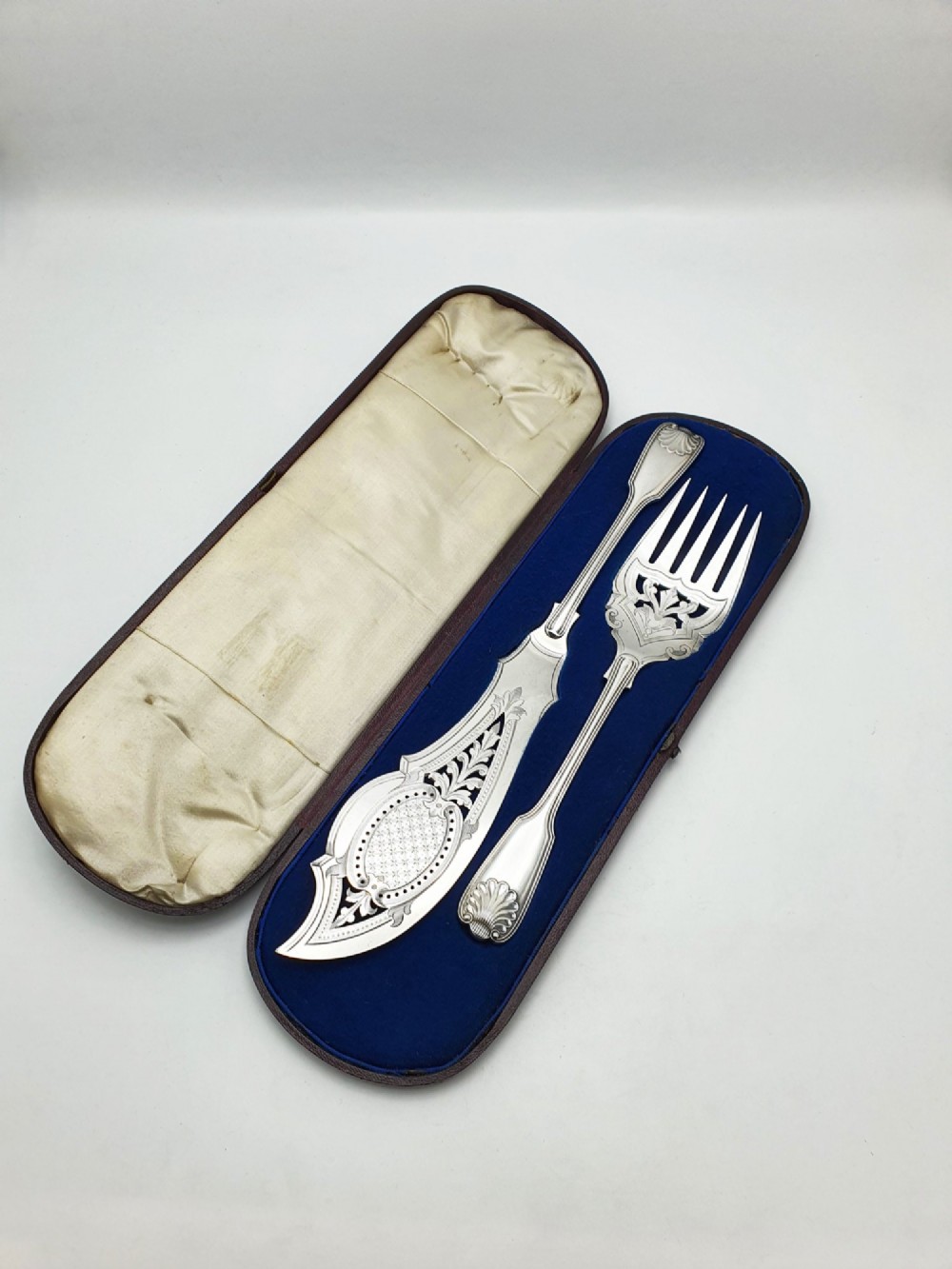 An antique Victorian silver-plated fish serving set with an engraved knife and fork presented in a fitted satin and velvet lined case.