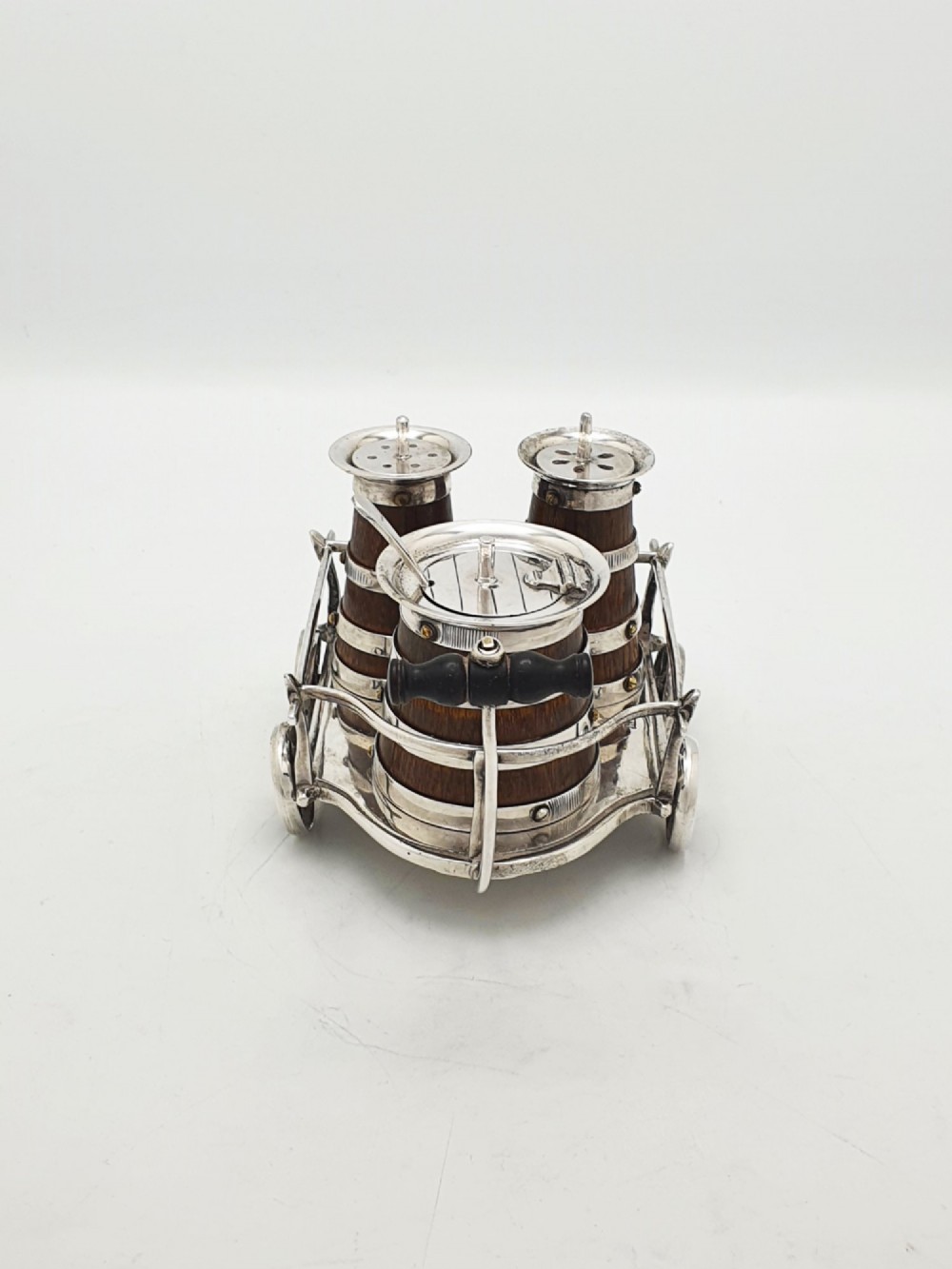 An antique Victorian silver-plated condiment set crafted as a miniature four-wheeled trolley holding three oak barrel-shaped containers. View III
