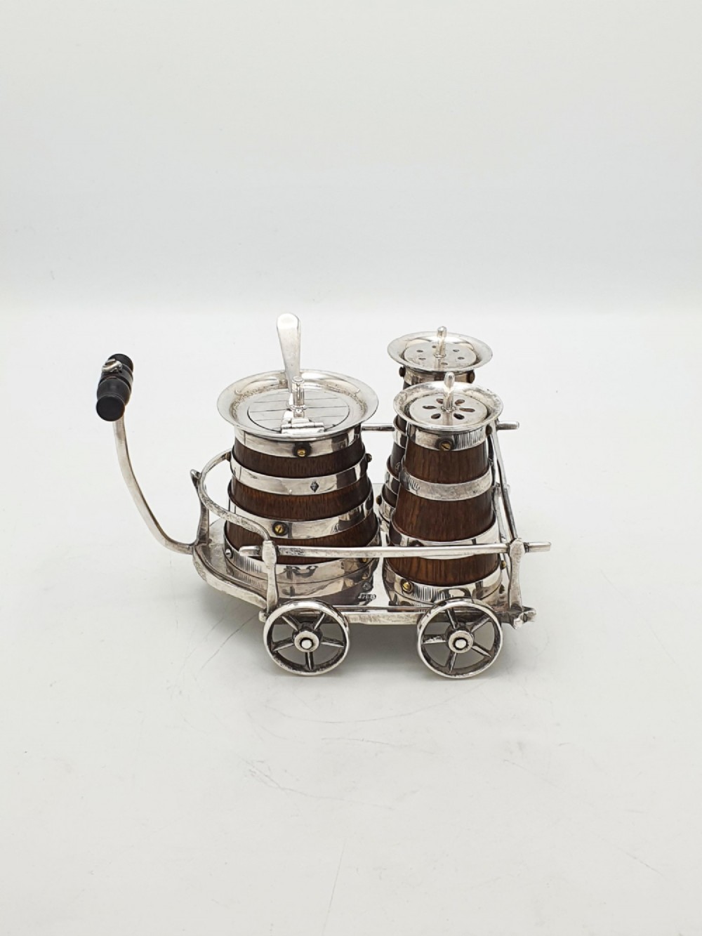 An antique Victorian silver-plated condiment set crafted as a miniature four-wheeled trolley holding three oak barrel-shaped containers. View IV