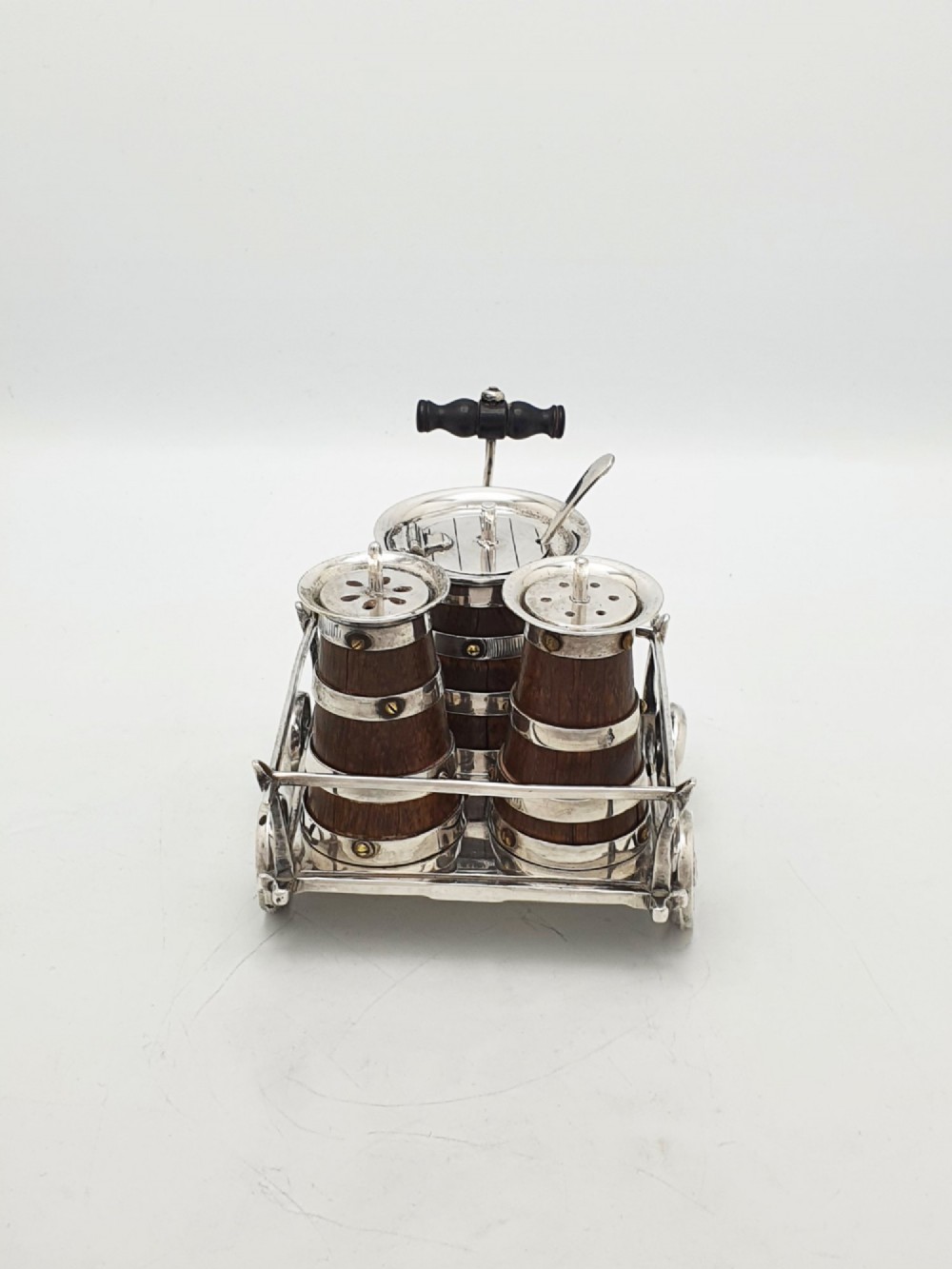 An antique Victorian silver-plated condiment set crafted as a miniature four-wheeled trolley holding three oak barrel-shaped containers. View V