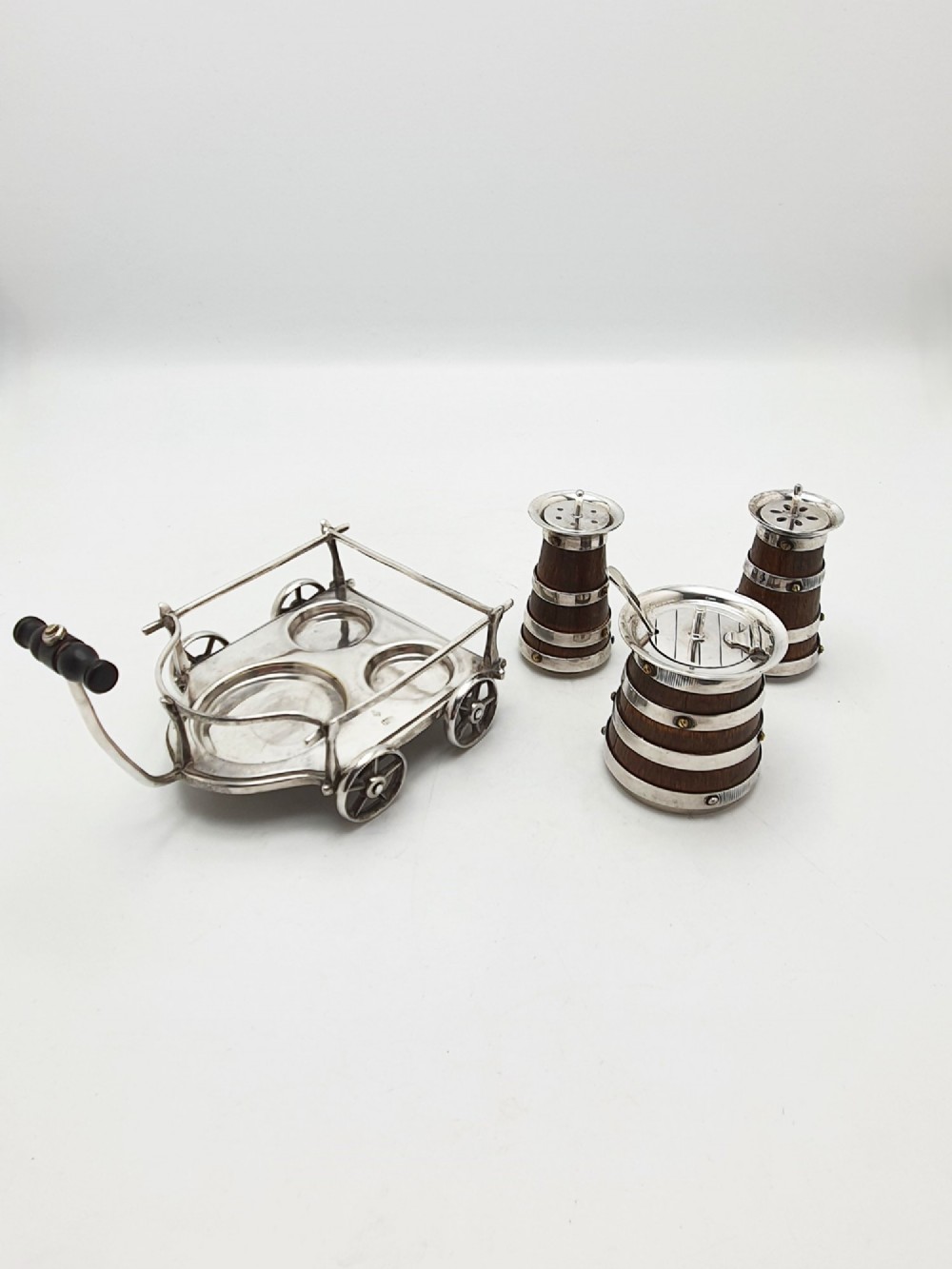 An antique Victorian silver-plated condiment set crafted as a miniature four-wheeled trolley holding three oak barrel-shaped containers. View VI