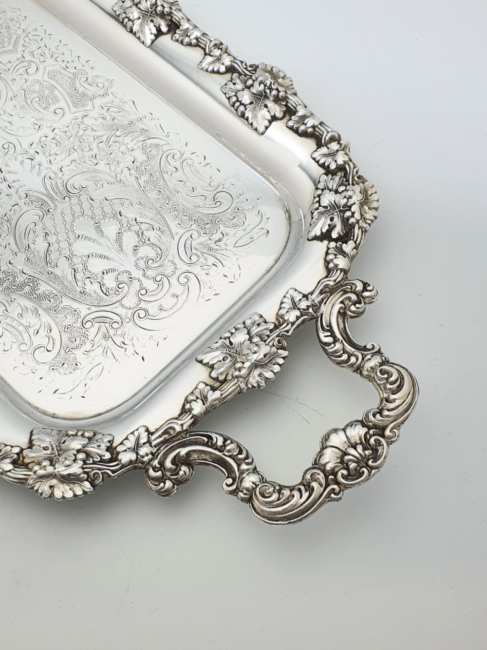 A long rectangular silver plated serving tray featuring an ornate grapevine motif rim, twin cast scroll handles, and an intricately chased floral central surface pattern. View II