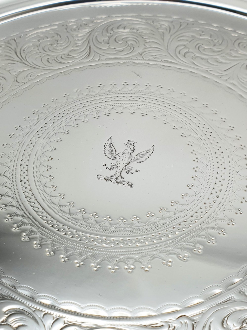 A set of three circular Victorian silver plated salvers arranged in graduated sizes, featuring beaded borders, detailed scroll engraving, and central crests. View VI