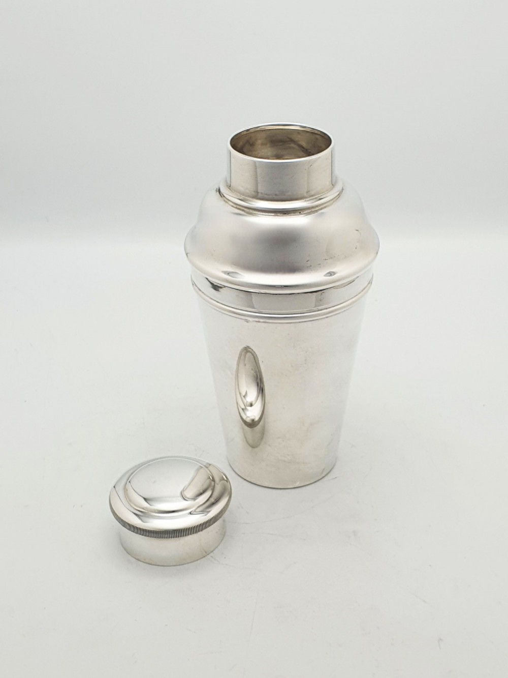 An Art Deco silver-plated cocktail shaker featuring a tapered body, stepped shoulder, and a milled-edge cap. View II