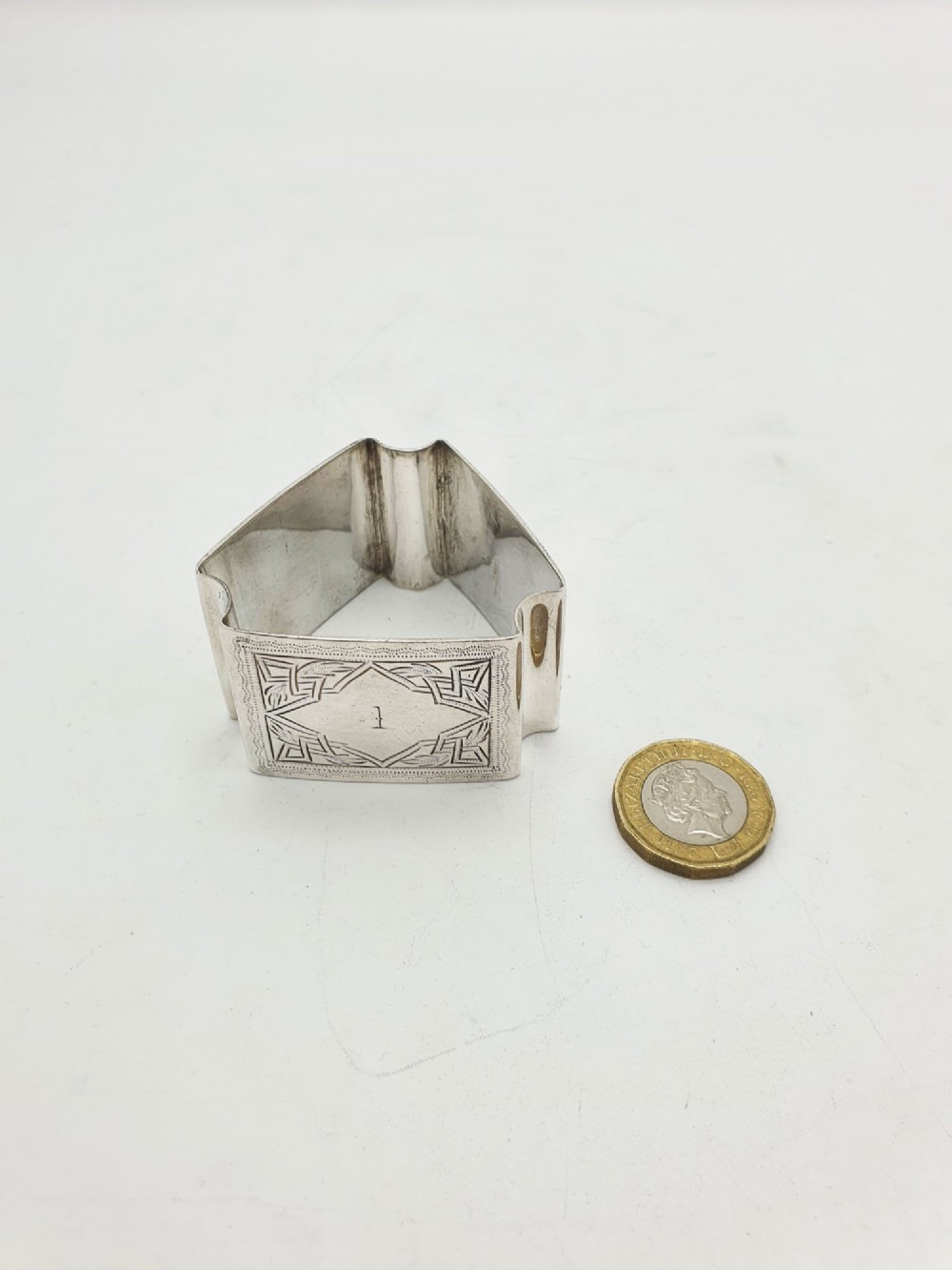 A set of six Edwardian silver-plated napkin rings numbered one through six with engraved geometric borders. View V