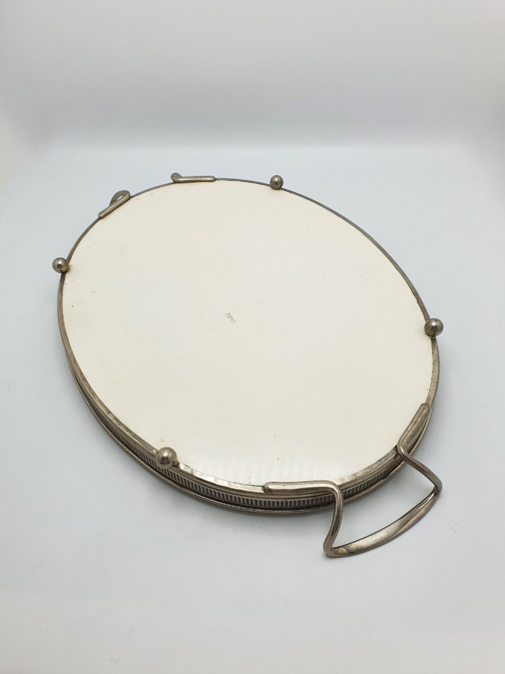 An antique oval serving tray featuring a pierced metal gallery rim, side handles, and an off-white ceramic base decorated with a blue floral garland. View V