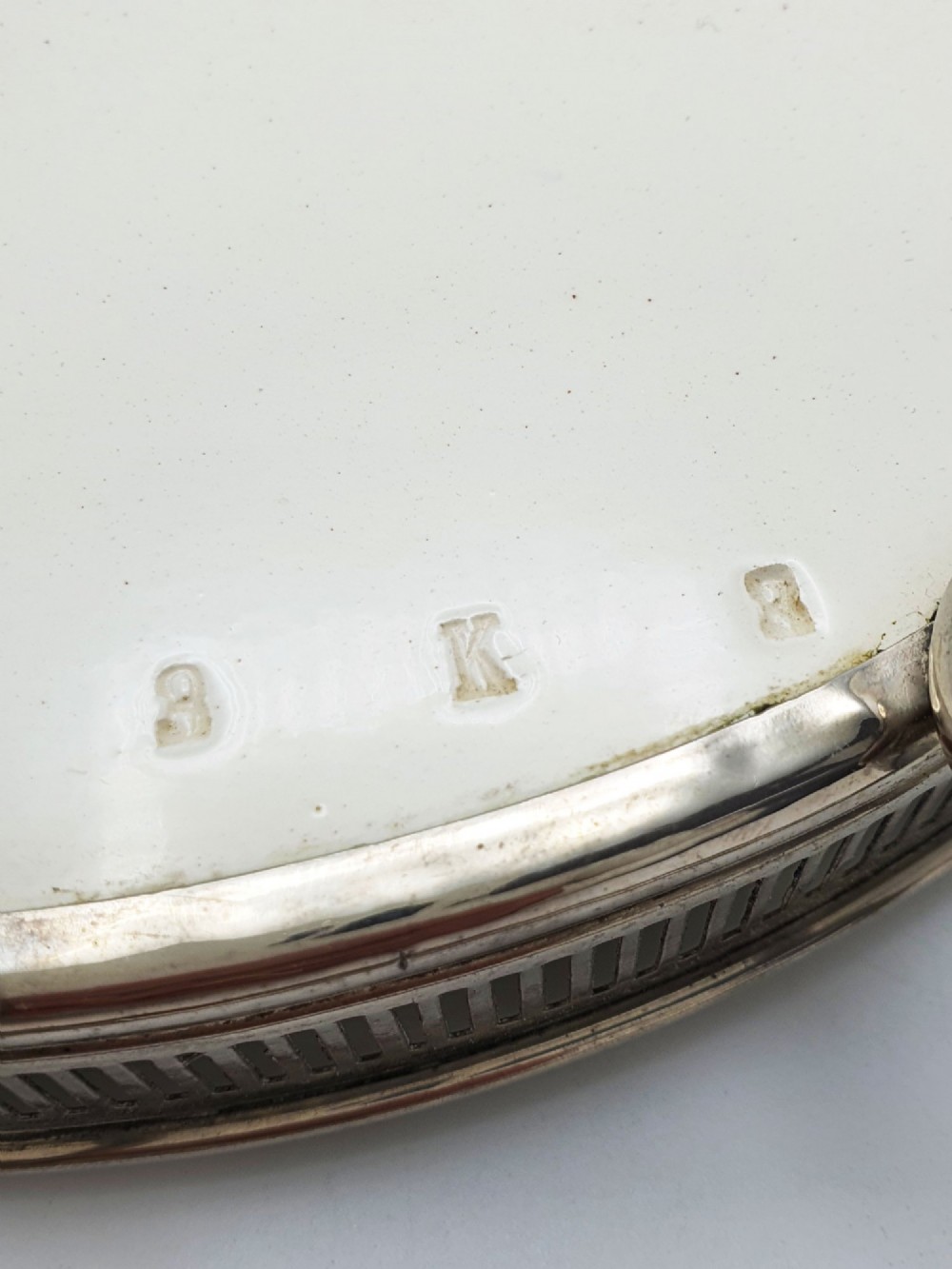 An antique oval serving tray featuring a pierced metal gallery rim, side handles, and an off-white ceramic base decorated with a blue floral garland. View VII