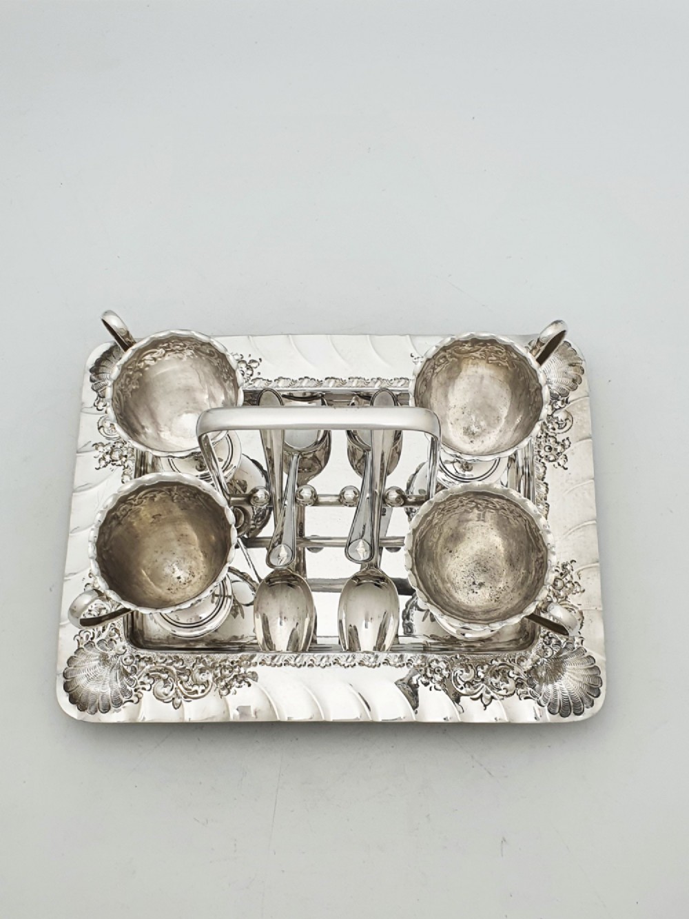 An Edwardian silver-plated egg cruet set with four embossed egg cups, four spoons, and an ornate tray with a central carry handle. View III