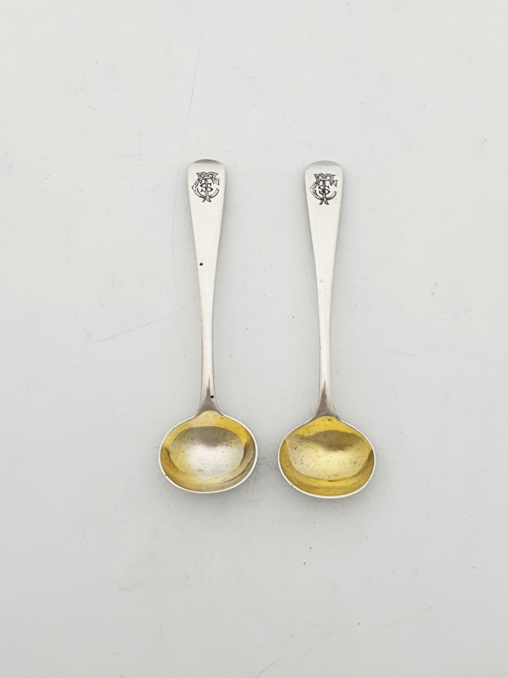 A pair of Edwardian sterling silver oval pedestal salt cellars with pierced filigree rims, dark cobalt blue glass liners, and matching silver salt spoons. View VI