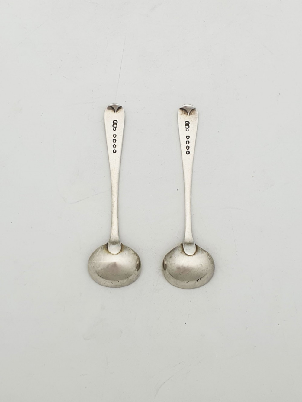 A pair of Edwardian sterling silver oval pedestal salt cellars with pierced filigree rims, dark cobalt blue glass liners, and matching silver salt spoons. View VII