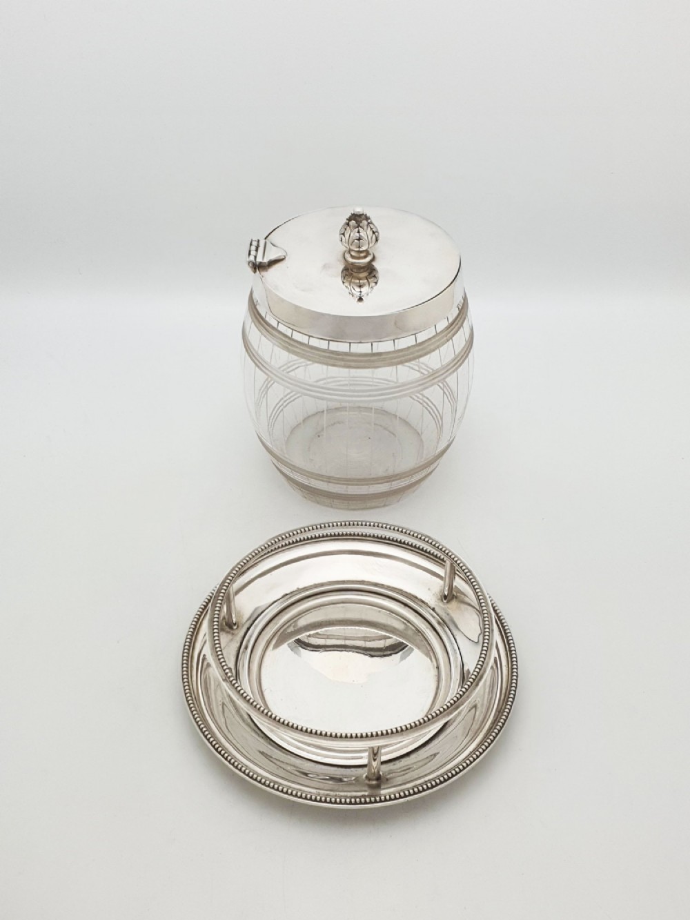 A Victorian cut glass barrel-shaped container with a silver-plated hinged lid and matching stand. View V