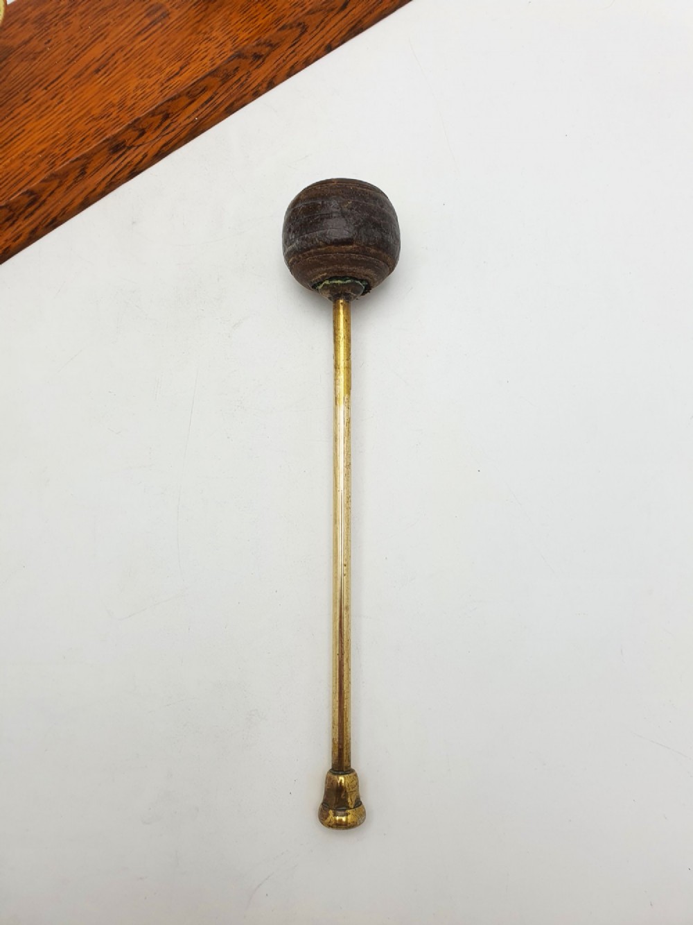 An antique brass circular gong with patterned etching suspended within a wavy brass frame on a polished rectangular oak base with a matching striker. View IX