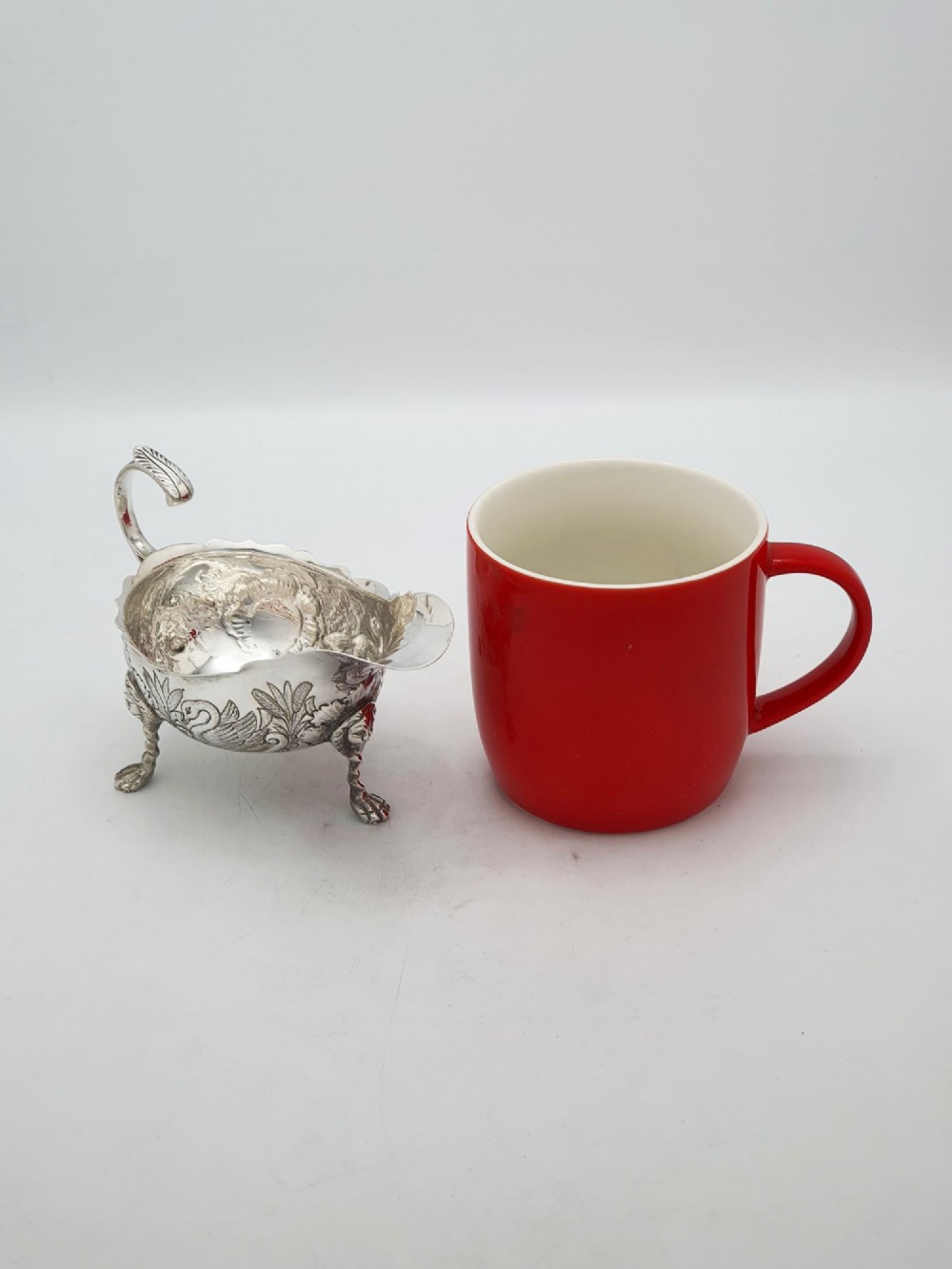 A pair of engraved silver-plated sauce boats with curved handles and decorated cabriole legs resting on a neutral background. View VII