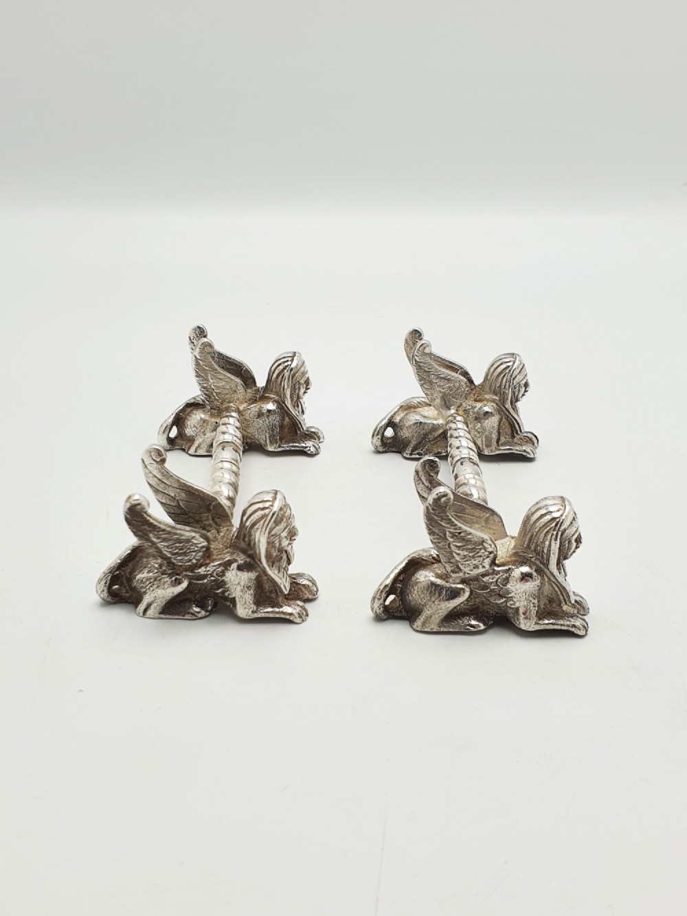A pair of Victorian silver-plated knife rests featuring winged sphinx end supports connected by a spiral twist bar. View III