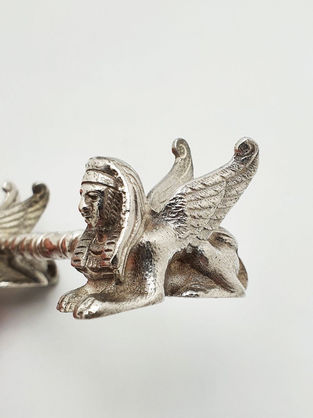 A pair of Victorian silver-plated knife rests featuring winged sphinx end supports connected by a spiral twist bar. View V