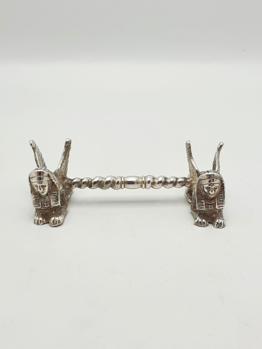 A pair of Victorian silver-plated knife rests featuring winged sphinx end supports connected by a spiral twist bar. View VI