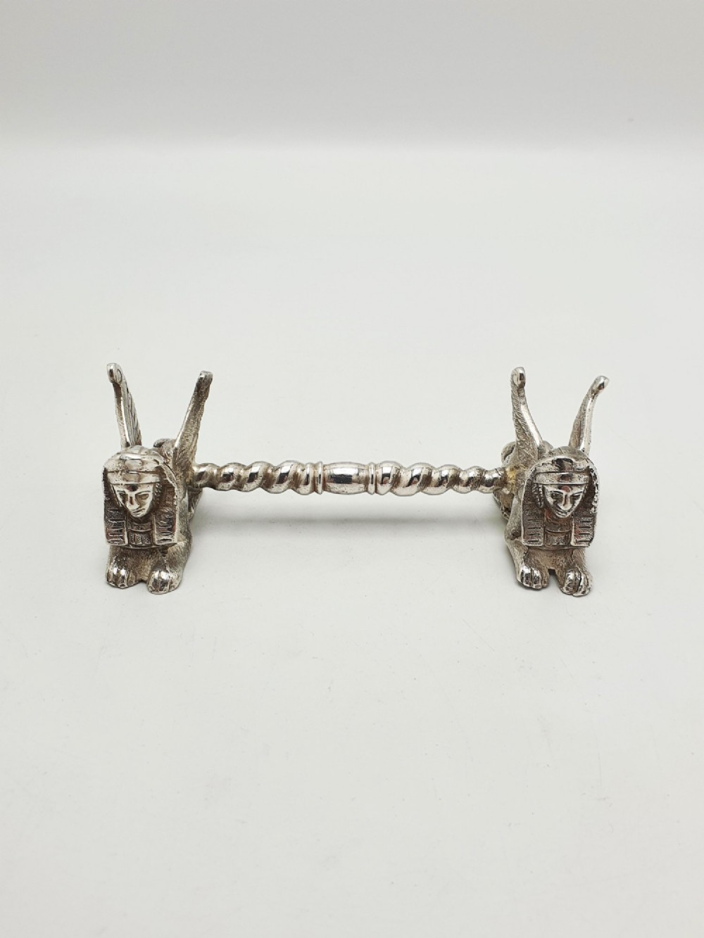 A pair of Victorian silver-plated knife rests featuring winged sphinx end supports connected by a spiral twist bar. View VII