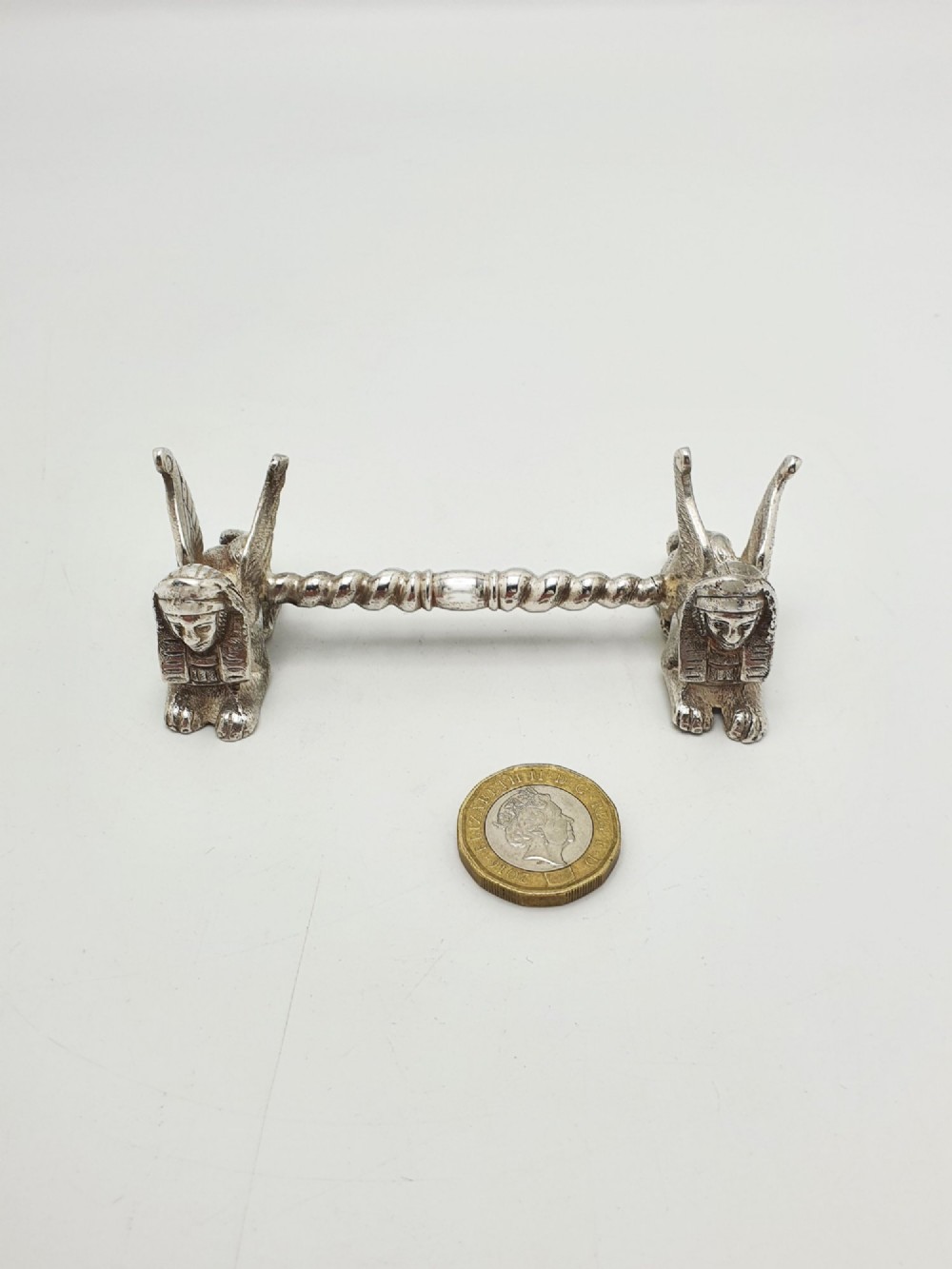 A pair of Victorian silver-plated knife rests featuring winged sphinx end supports connected by a spiral twist bar. View VIII