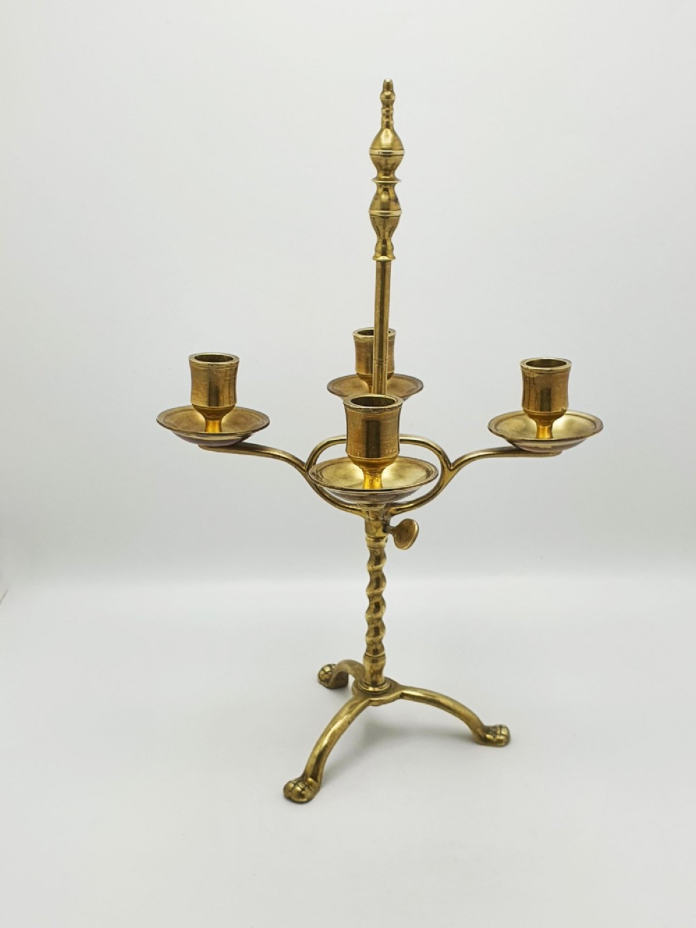 A pair of antique brass four-light adjustable candelabras featuring turned central shafts, tripod feet, and finials. View V