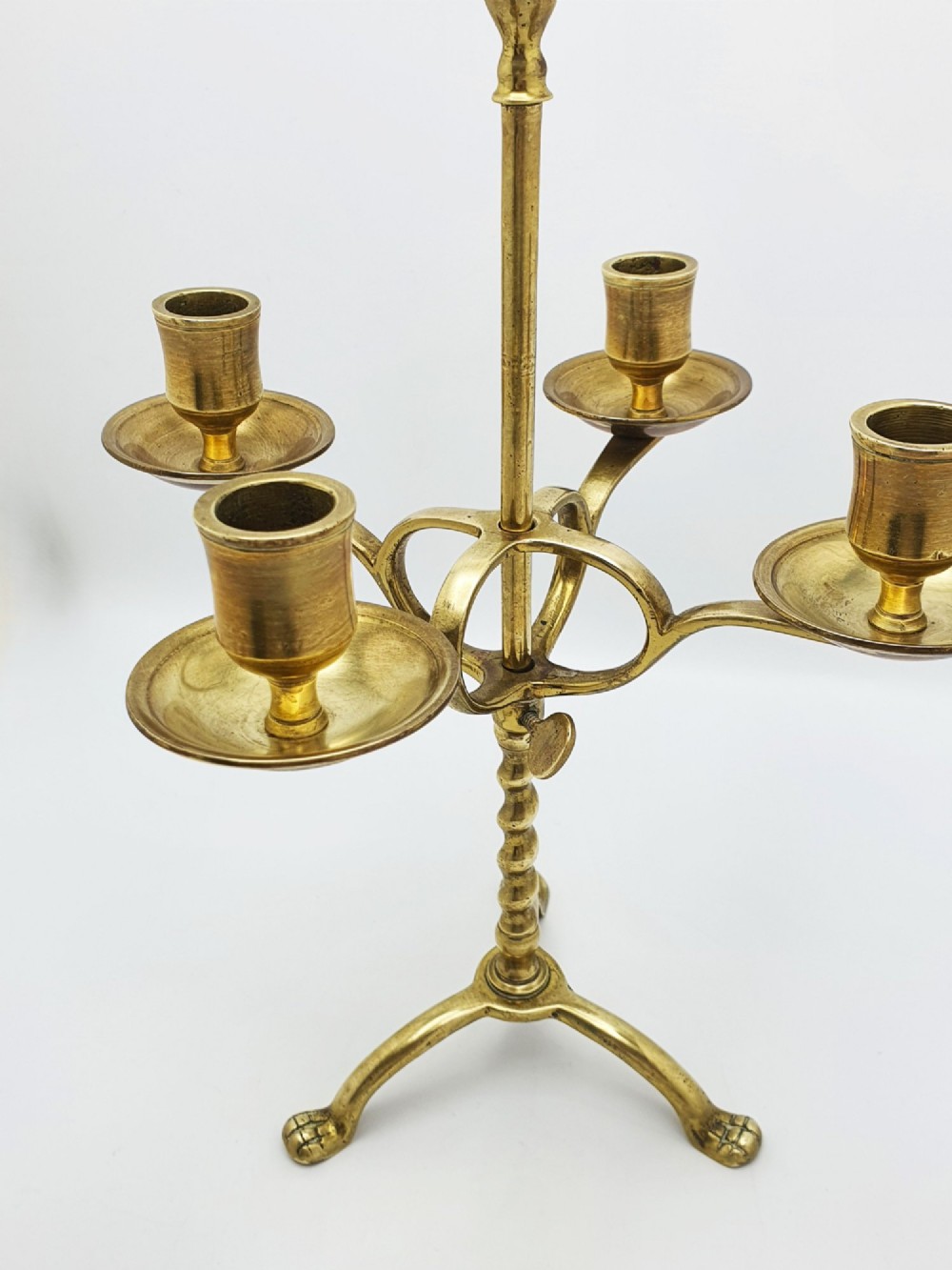 A pair of antique brass four-light adjustable candelabras featuring turned central shafts, tripod feet, and finials. View VI