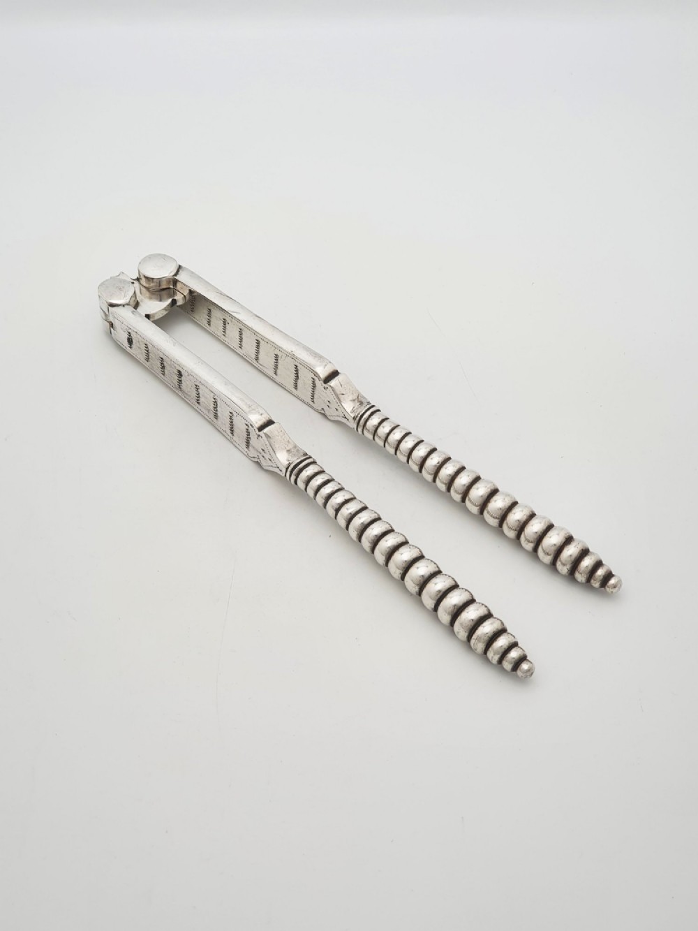 A pair of Victorian silver-plated lobster crackers featuring textured ridged handles and a hinged double-jaw mechanism. View III