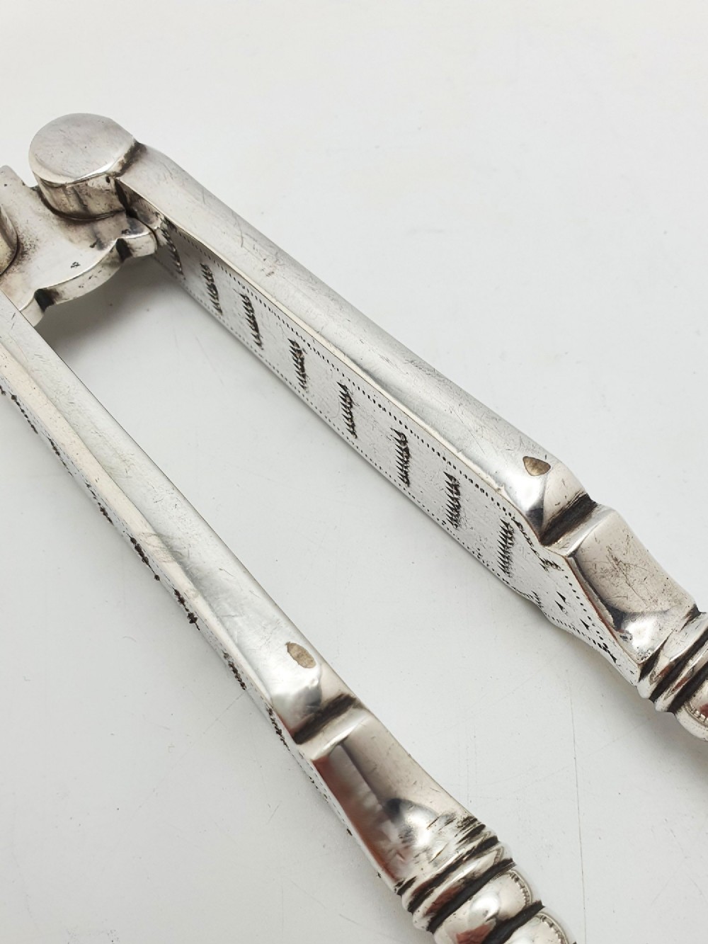 A pair of Victorian silver-plated lobster crackers featuring textured ridged handles and a hinged double-jaw mechanism. View V