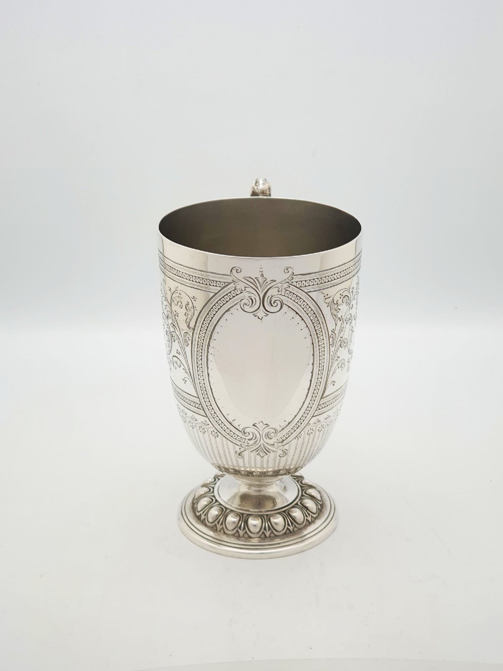 An Edwardian silver-plated tankard with intricate foliate engraving, a fluted pedestal base, and a decorative handle sculpted with an owl motif. View II