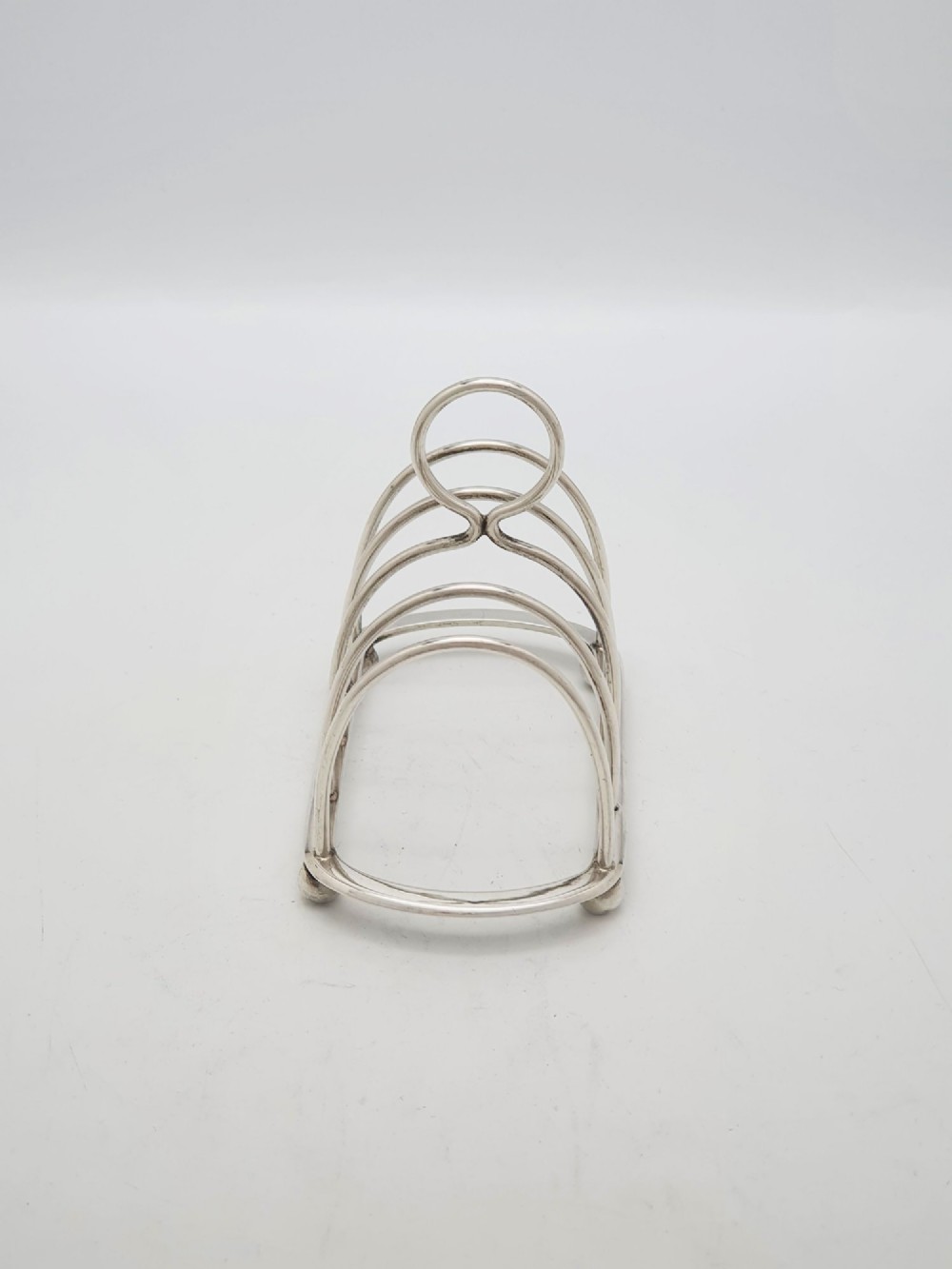 A small late Victorian sterling silver toast rack featuring five arched divisions, a central ring handle, and four ball feet. View III