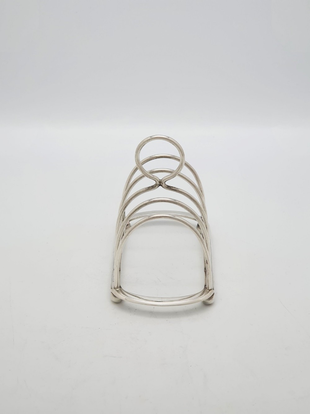 A small late Victorian sterling silver toast rack featuring five arched divisions, a central ring handle, and four ball feet. View V