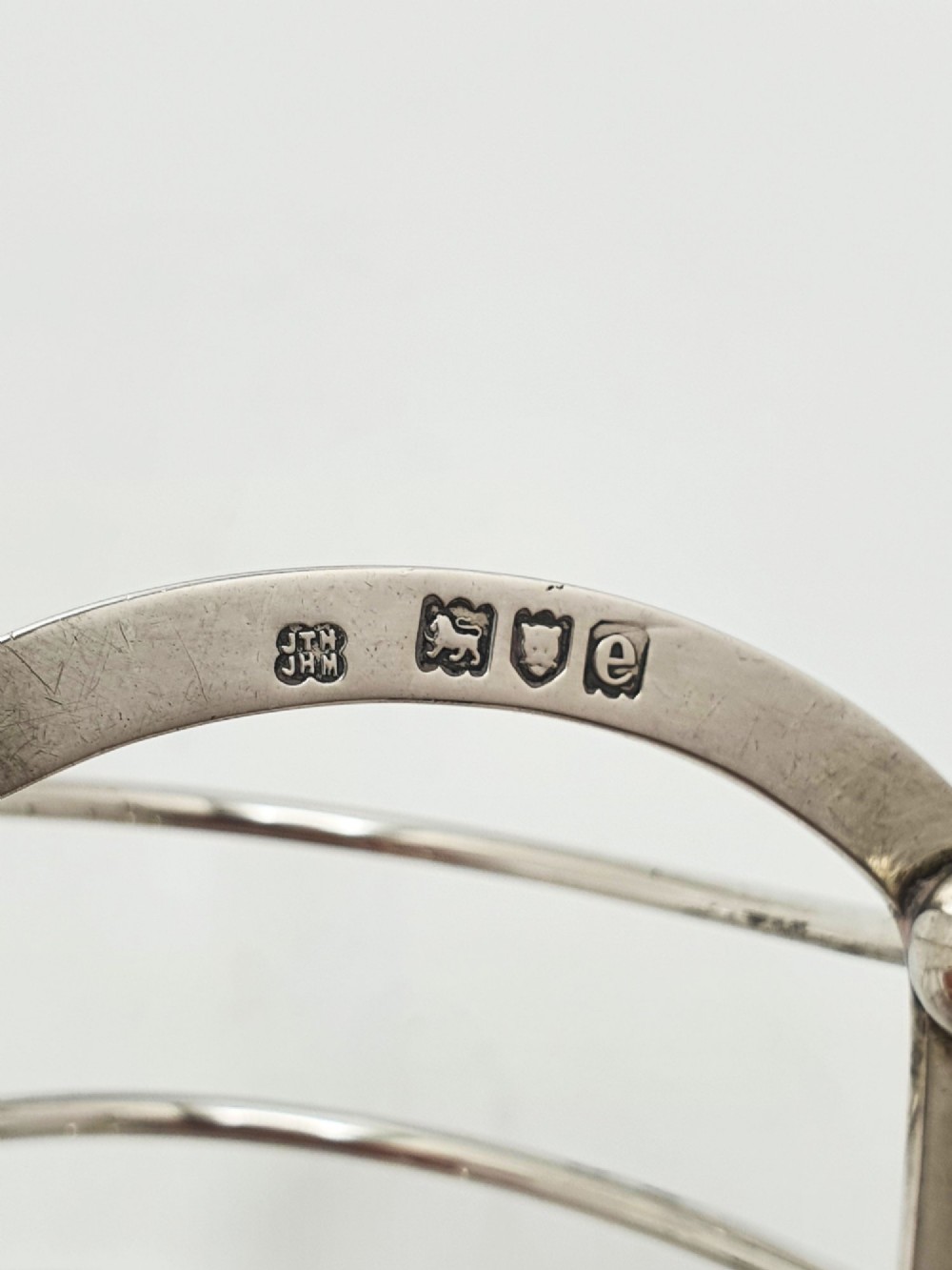A small late Victorian sterling silver toast rack featuring five arched divisions, a central ring handle, and four ball feet. View VI