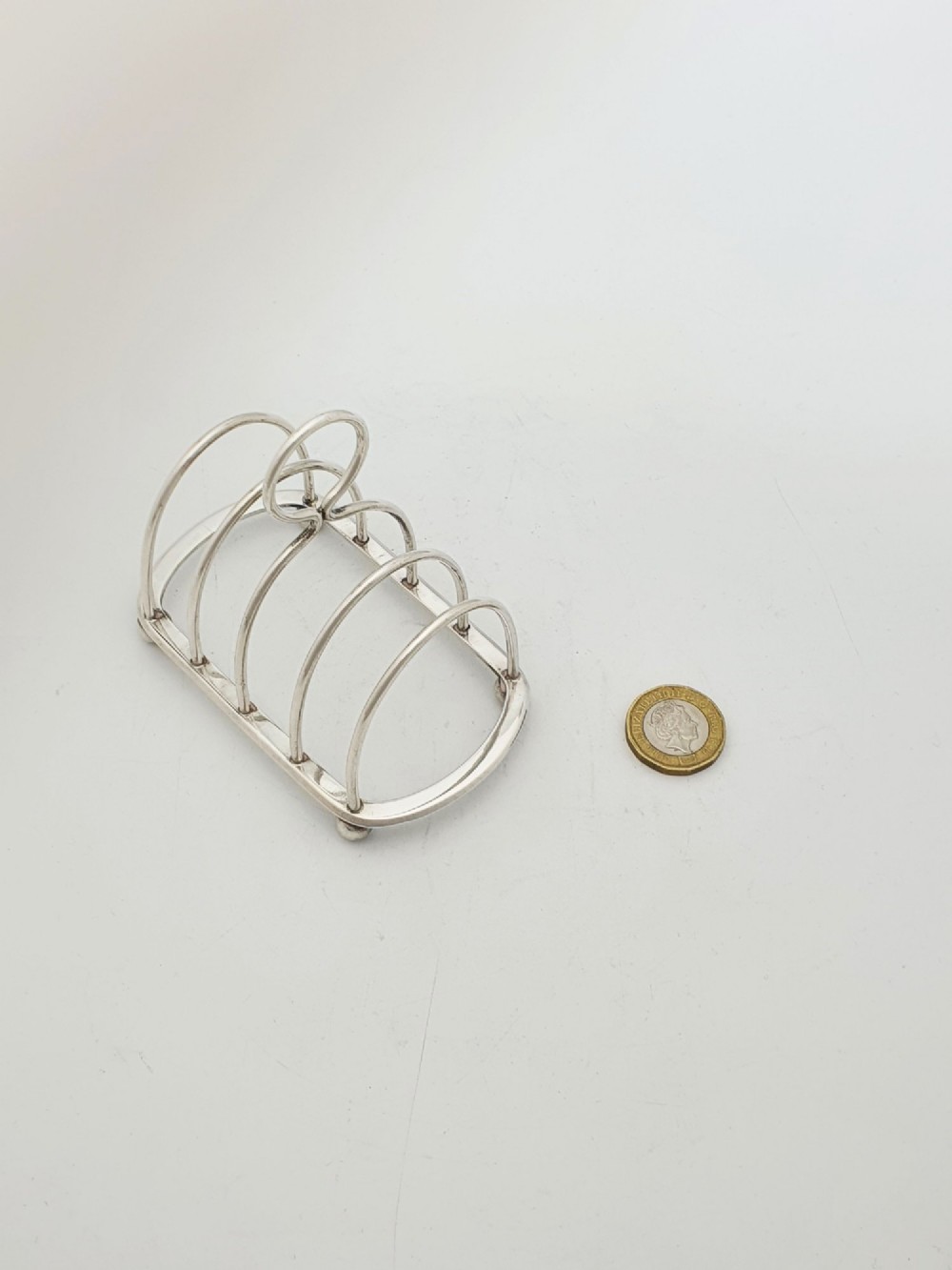 A small late Victorian sterling silver toast rack featuring five arched divisions, a central ring handle, and four ball feet. View VIII
