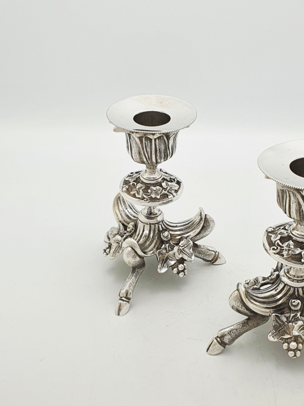 A pair of Victorian silver-plated candlesticks featuring fluted holders, grape leaf ornamentation, and tripod bases shaped like animal hooves. View III