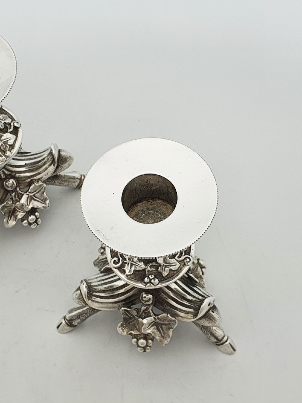 A pair of Victorian silver-plated candlesticks featuring fluted holders, grape leaf ornamentation, and tripod bases shaped like animal hooves. View IV