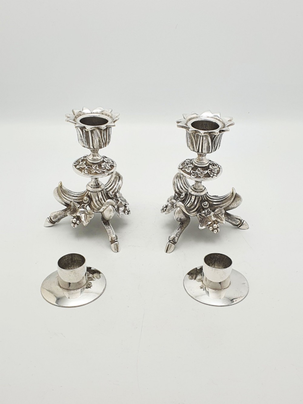 A pair of Victorian silver-plated candlesticks featuring fluted holders, grape leaf ornamentation, and tripod bases shaped like animal hooves. View VII