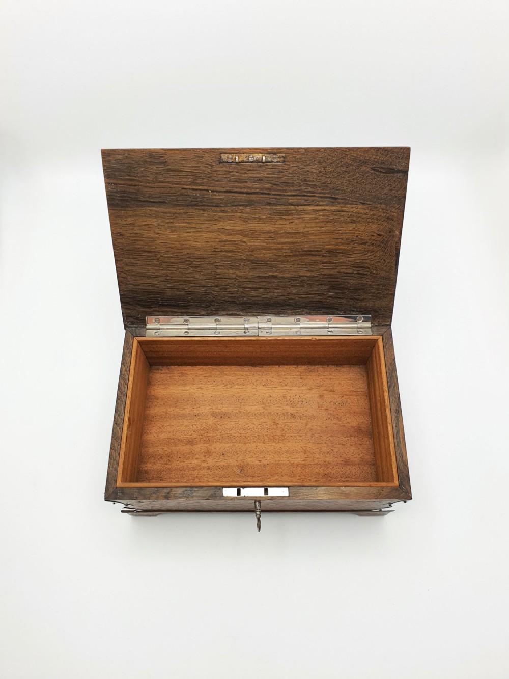 An Edwardian oak cigar box featuring decorative sterling silver corner mounts, a central shaped silver plaque, and a front keyhole with key. View IV