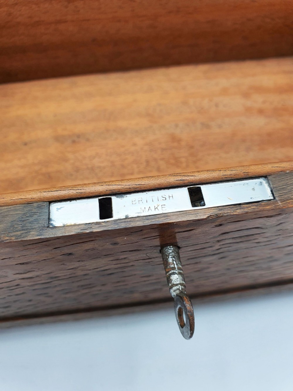 An Edwardian oak cigar box featuring decorative sterling silver corner mounts, a central shaped silver plaque, and a front keyhole with key. View V