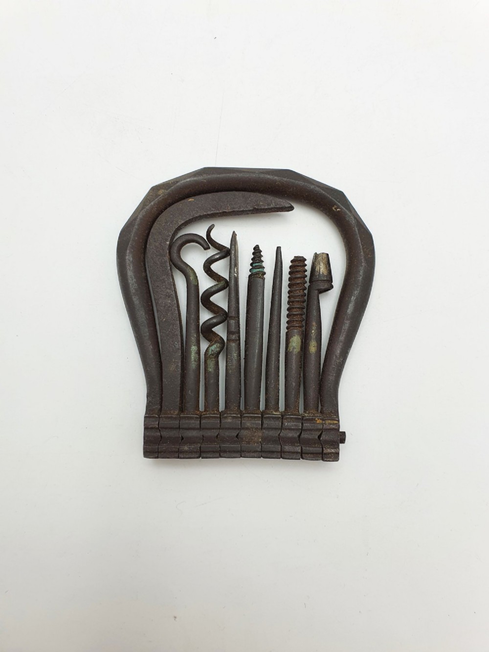 An antique Victorian dark iron folding multi-tool featuring multiple hinged implements including a corkscrew, gimlet, and spike set within a curved metal frame.