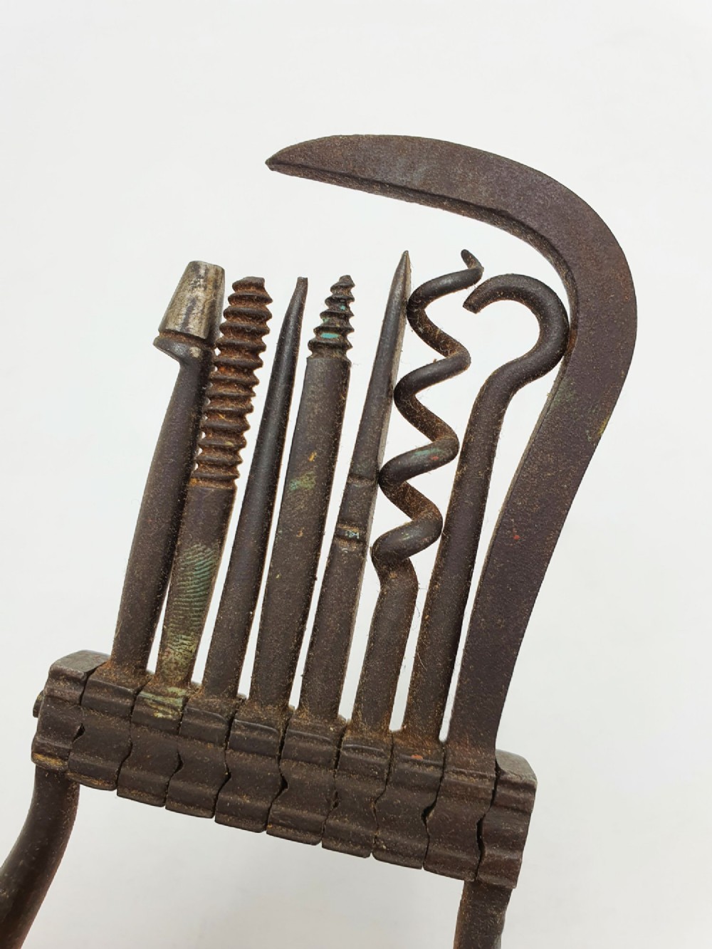 An antique Victorian dark iron folding multi-tool featuring multiple hinged implements including a corkscrew, gimlet, and spike set within a curved metal frame. View IV