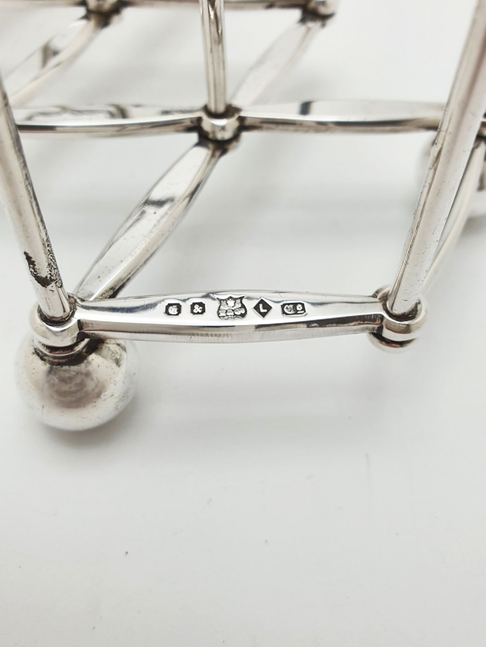 An antique silver-plated extending toast rack featuring an articulated concertina base, arched dividers, ball feet, and a central loop handle. View IV