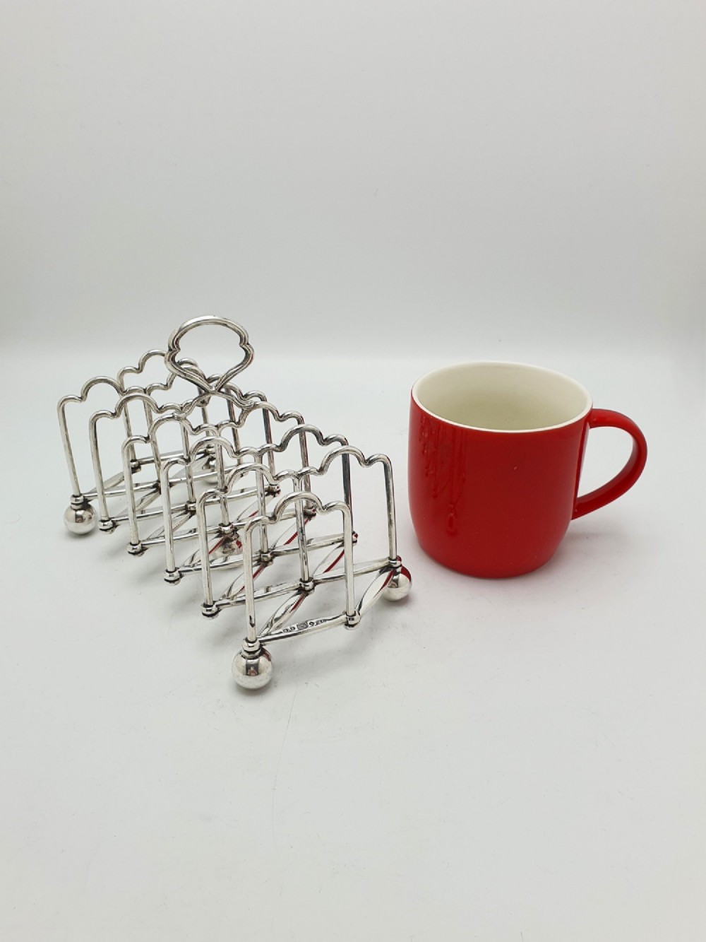 An antique silver-plated extending toast rack featuring an articulated concertina base, arched dividers, ball feet, and a central loop handle. View VI