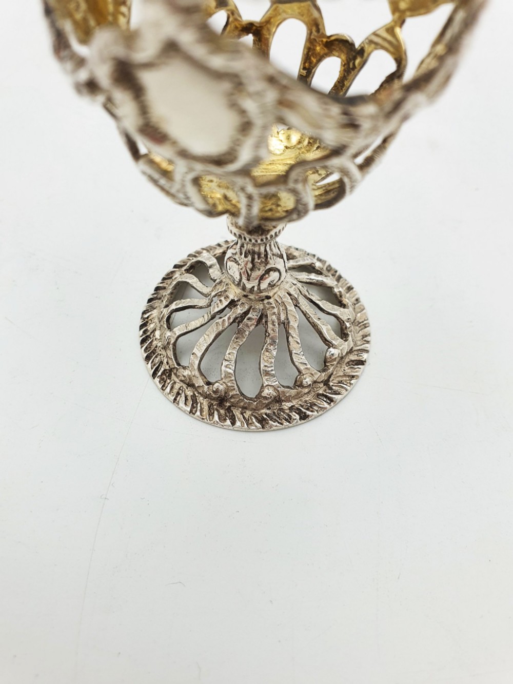 An Edwardian sterling silver egg cup featuring openwork lattice carving, a gilded interior wash, and a footed pedestal base. View IV