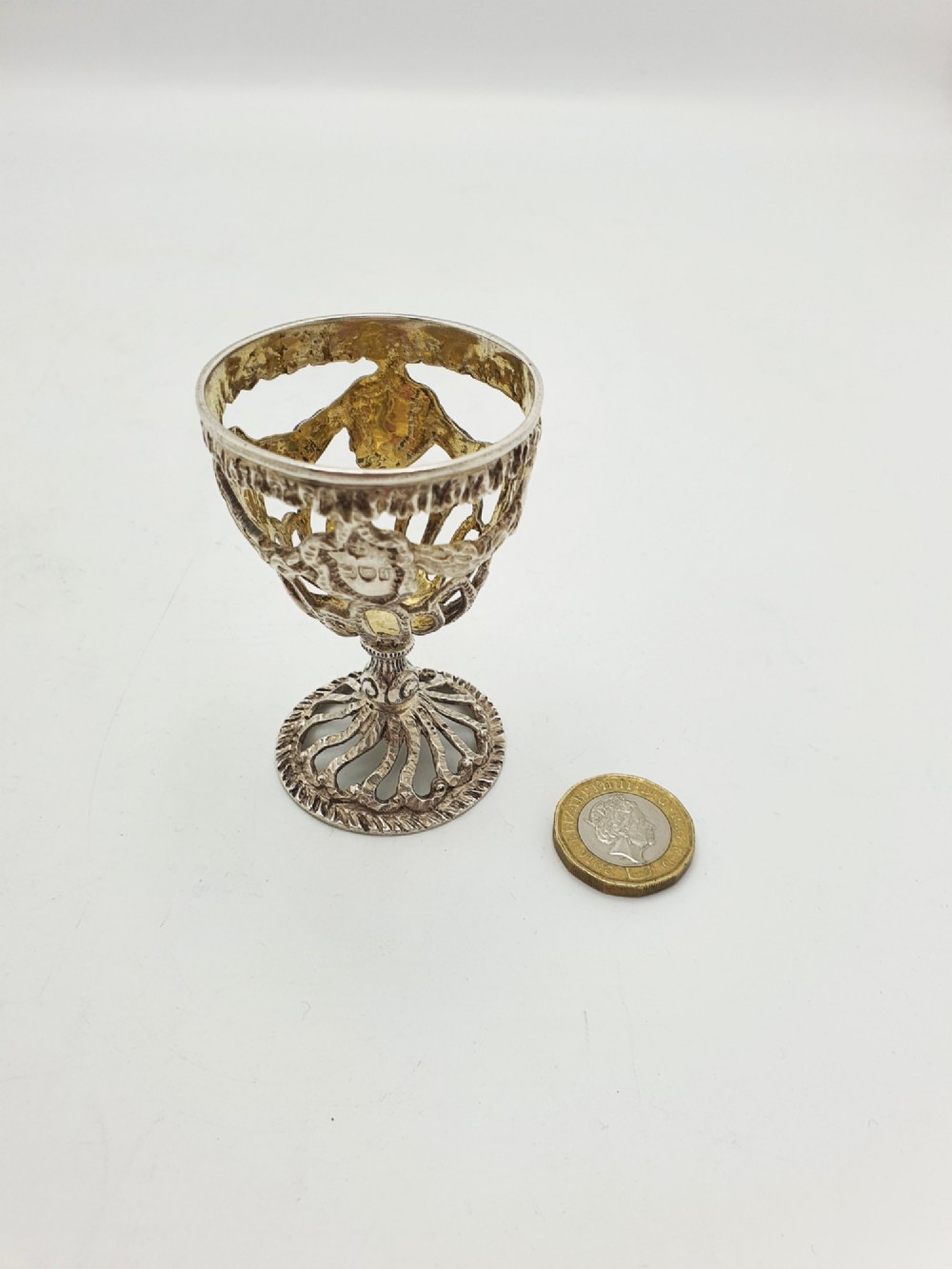 An Edwardian sterling silver egg cup featuring openwork lattice carving, a gilded interior wash, and a footed pedestal base. View VI